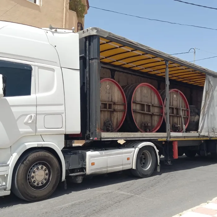 Camión aparcado en la calle con e remolque medio abierto.