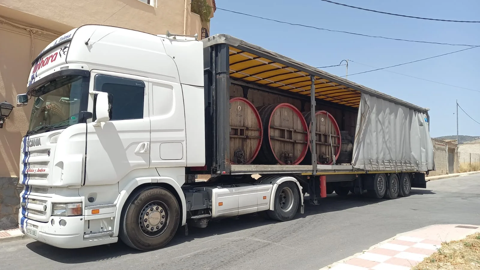 Camión aparcado en la calle con e remolque medio abierto.